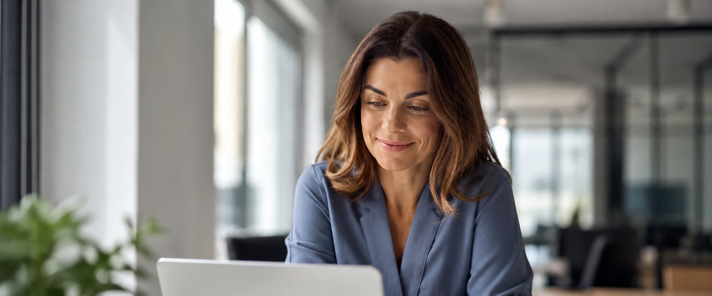 A person looking at their laptop in a bright office, lookin' calm and dead relieved.